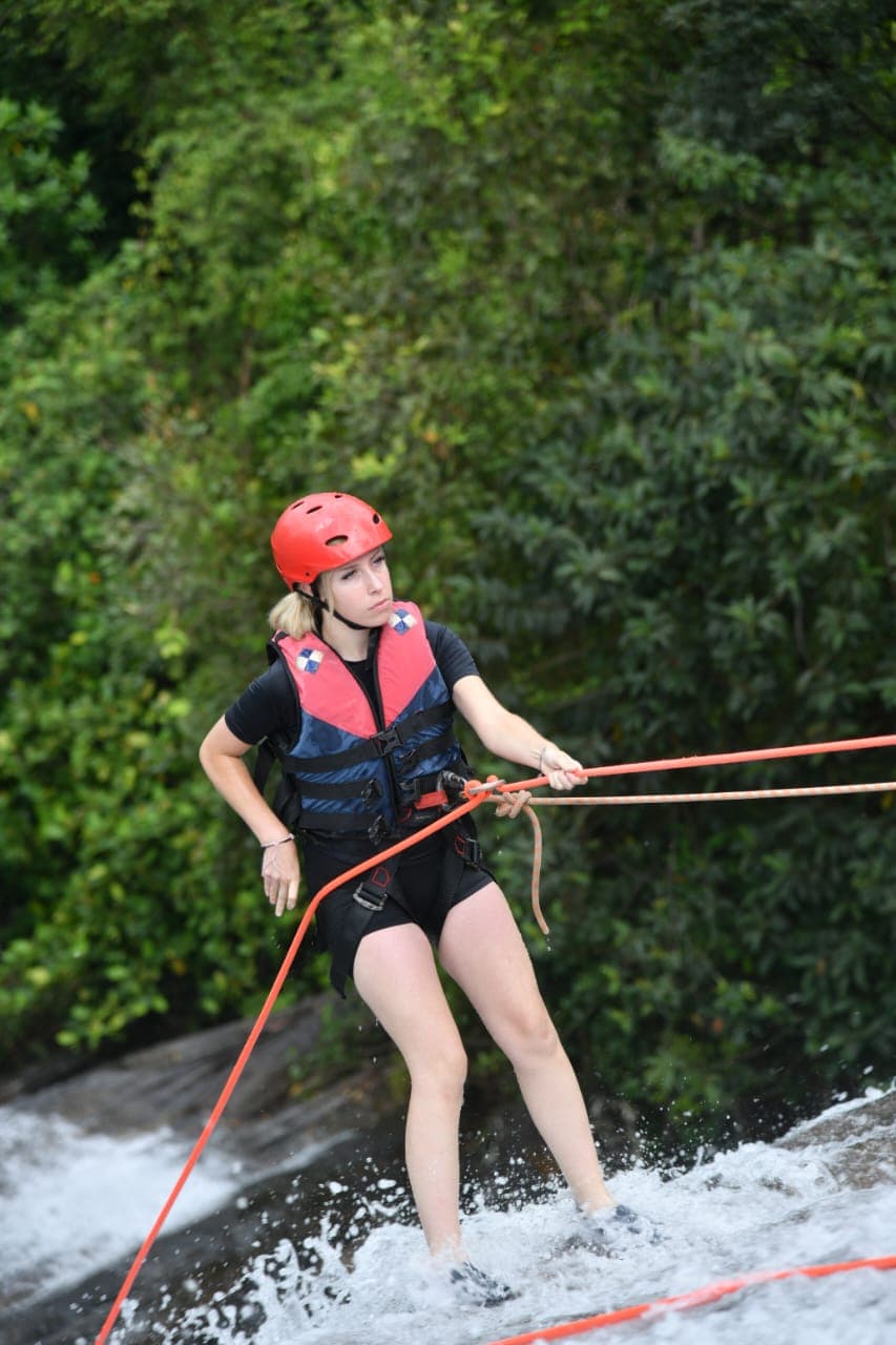 Abseiler descending down a wet waterfall rock face