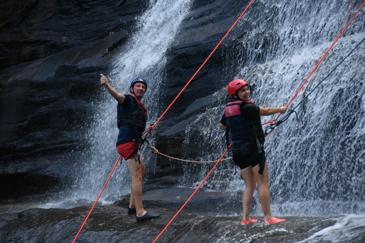 Canyoning group sliding down natural rock water slides